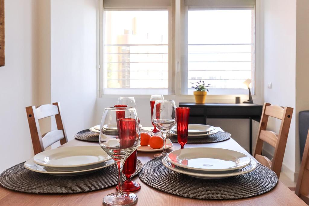 a dining room table with plates and wine glasses at Lisbon Flower 360º - Your Lovely Flat with Pool and Parking in Lisbon