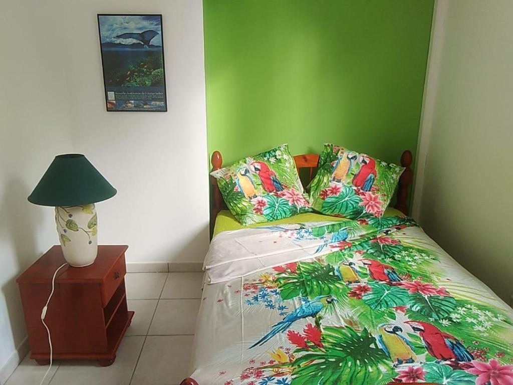 ein Schlafzimmer mit einem Bett und einer Lampe auf einem Nachttisch in der Unterkunft Bas de villa , Résidence Venus calme, vue sur mer in La Trinité