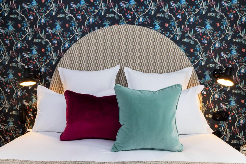 1 cama con 4 almohadas frente a una pared floral en Hotel Fior d'Aliza en París