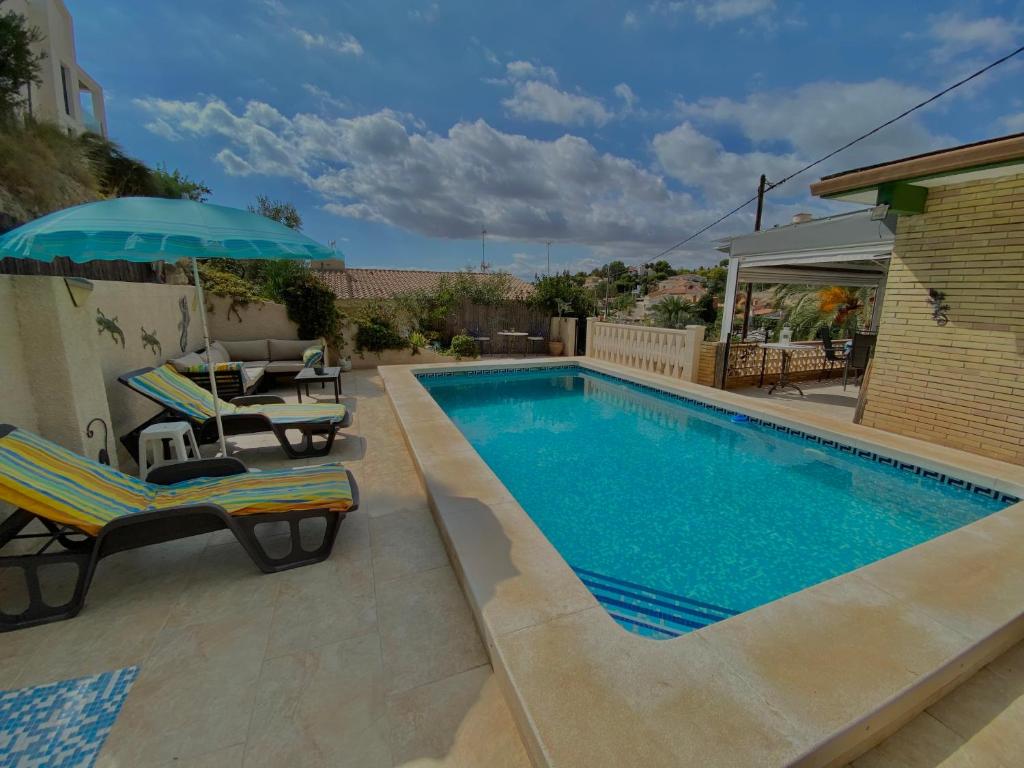 - une piscine avec 2 chaises et un parasol dans l'établissement Llamedos Apartment Private Pool, à El Campello