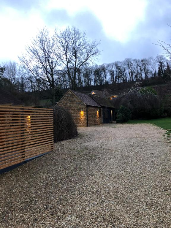 Un granero con una valla delante. en Wisteria Cottage - Hillside Holiday Cottages, Cotswolds, en Warmington