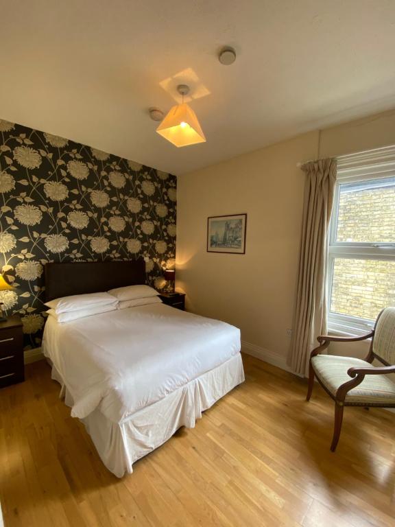 a bedroom with a bed and a chair and a window at Homerton House Apartments in Cambridge