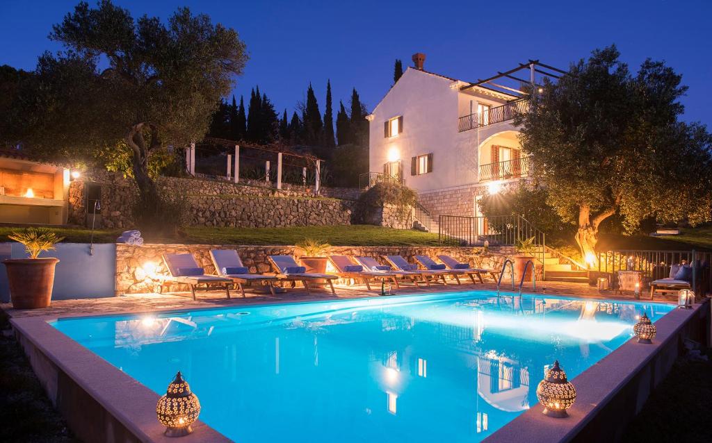 a swimming pool with chairs and a house in the background at Villa Sunrise in Gornji Brgat