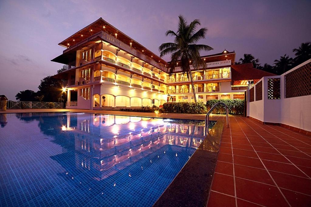 un hotel con piscina frente a un edificio en Aadisaktthi Leisure Resort, Kovalam en Thiruvananthapuram