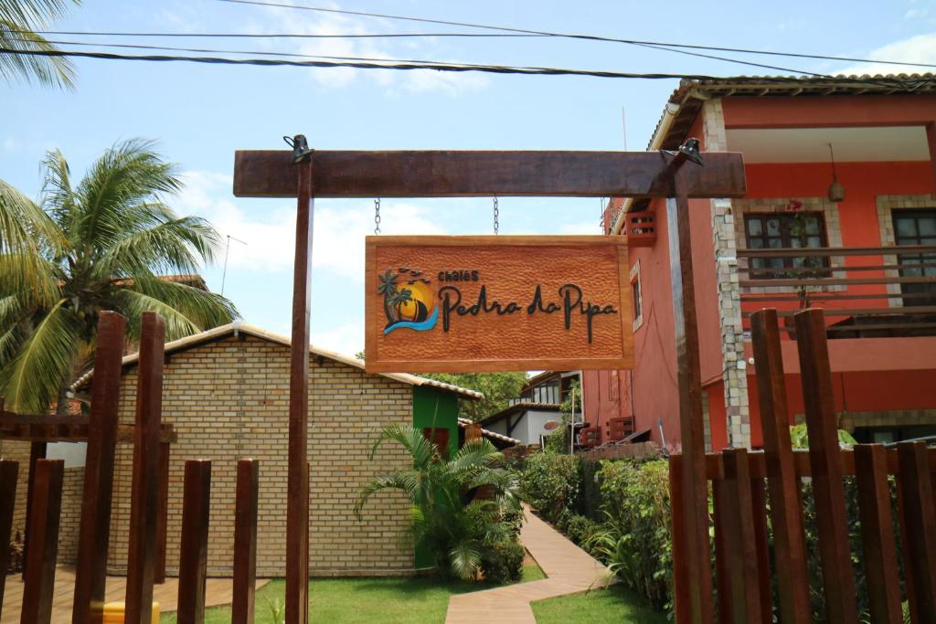 a sign hanging from a fence in front of a building at Chalés Pedra da Pipa in Pipa