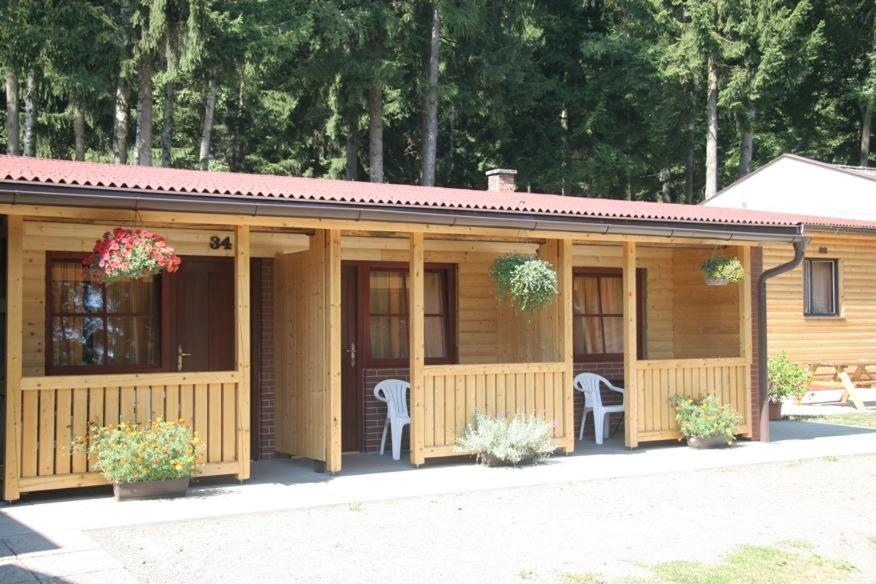 a wooden cabin with two chairs and flowers at Chatový areál Zděřina in Police nad Metují