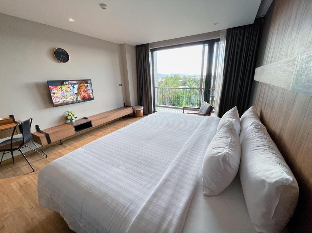una camera da letto con un grande letto bianco con una grande finestra di The Teak Hotel a Mae Sot