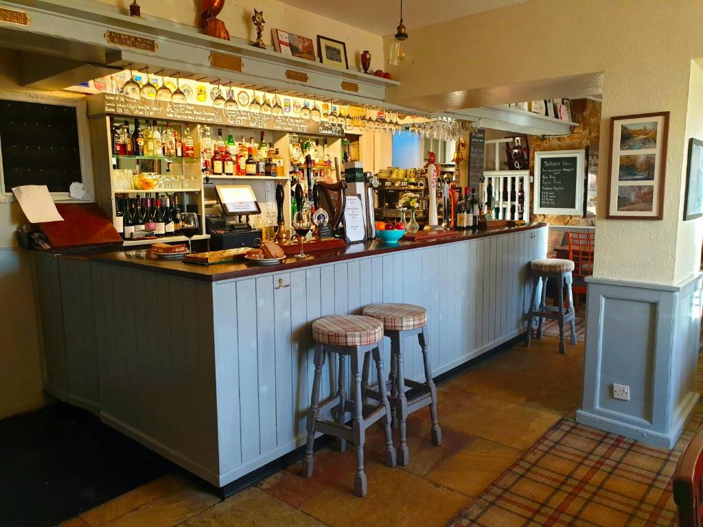 a bar with stools in the middle of a room at The Clarendon Country Pub with rooms in Grassington