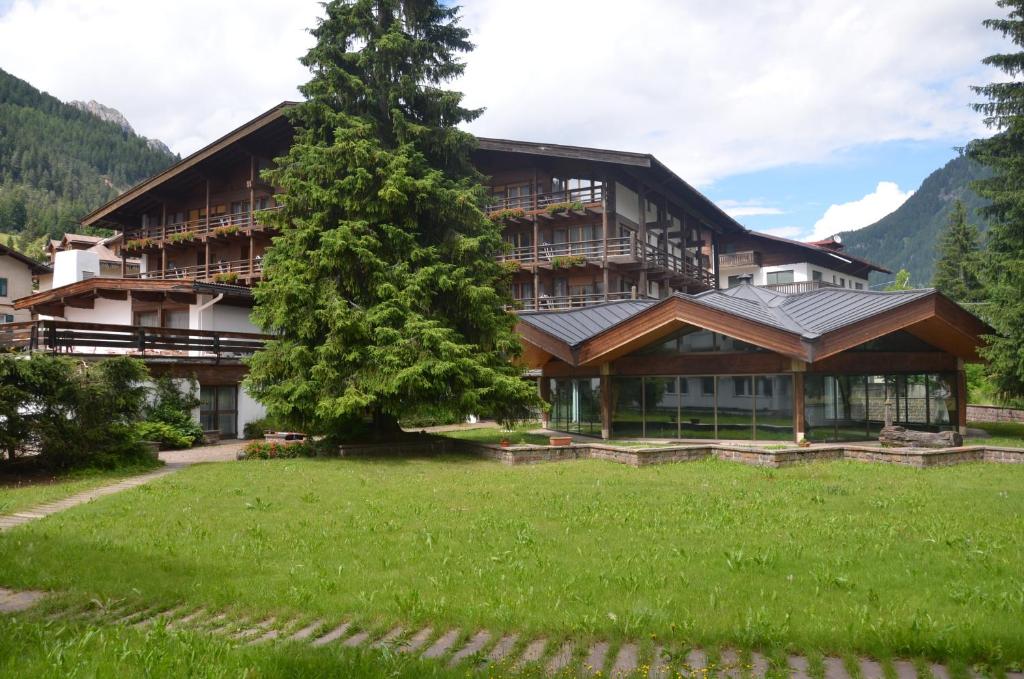 a large building with a tree in front of it at Hotel Trento in Pozza di Fassa