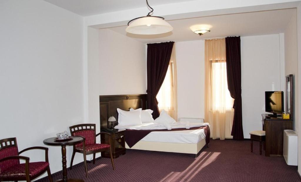 a hotel room with a bed and a table and chairs at Hanul Domnesc in Braşov