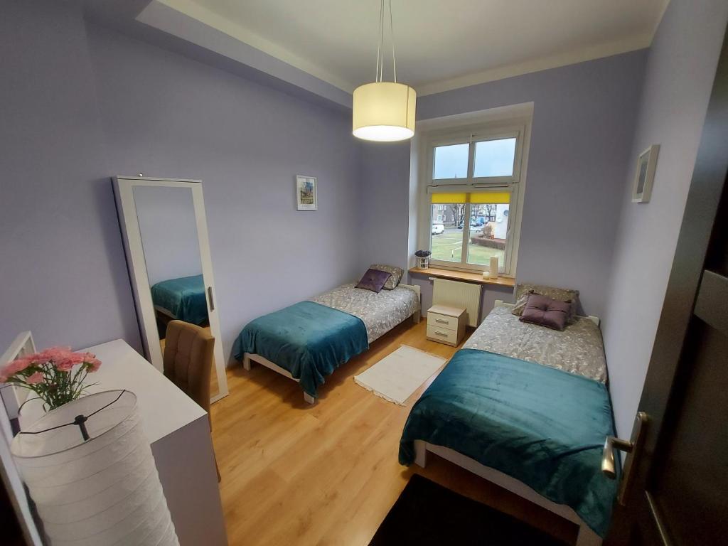 Habitación pequeña con 2 camas y espejo. en Apartament Mariacka, en Nysa