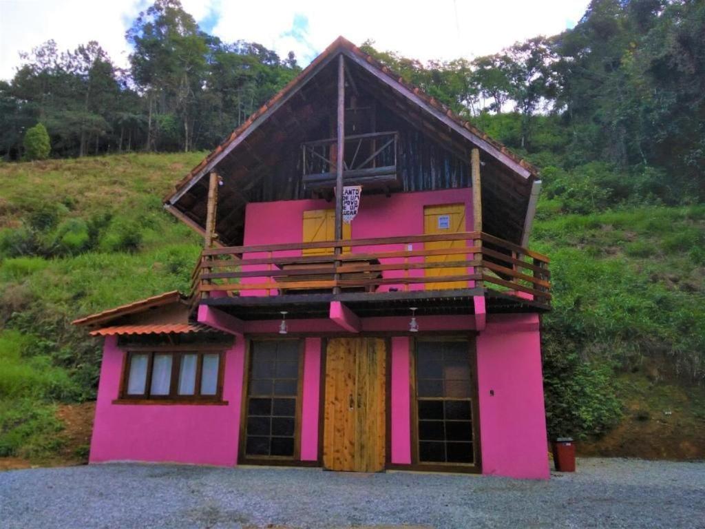 een roze huis met een balkon erop bij Bangalô Boa Ventura in Lumiar