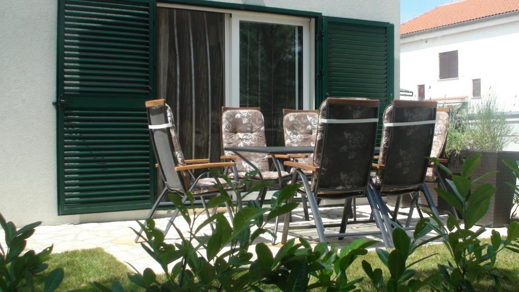 a group of chairs sitting around a table on a patio at Apartments Eva in Malinska
