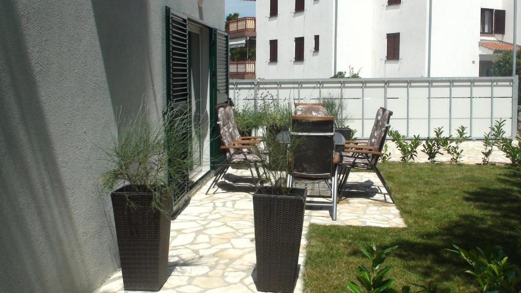patio z krzesłami i grillem na boku domu w obiekcie Apartments Eva w mieście Malinska