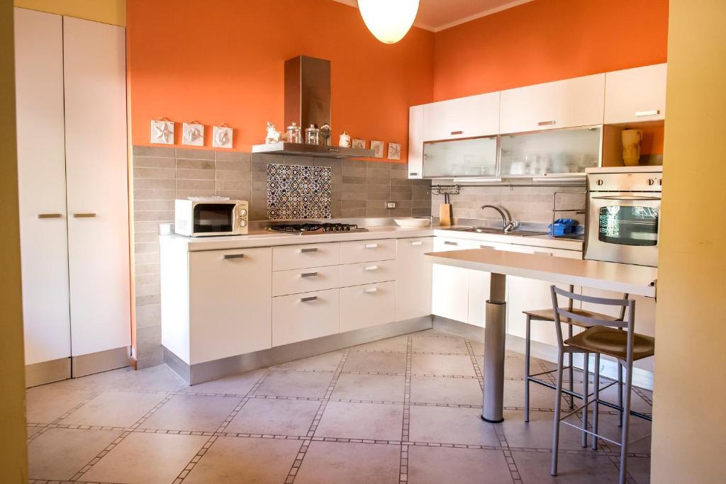 a kitchen with white cabinets and an orange wall at S34 - Sirolo, quadrilocale in centro arredato con gusto in Sirolo