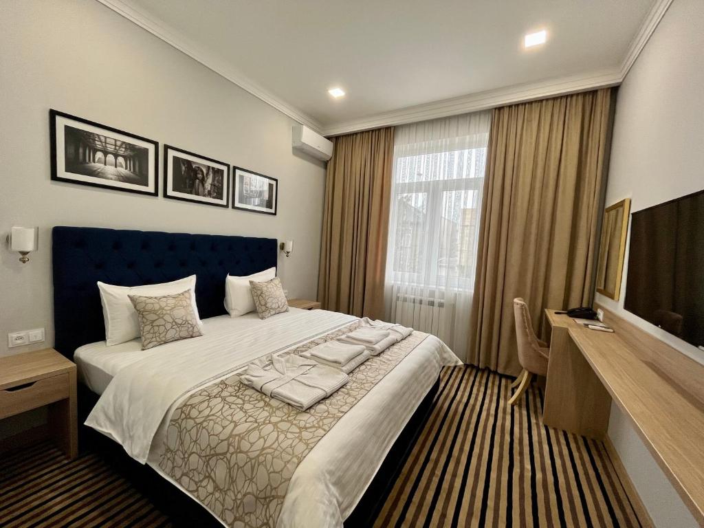 ein Schlafzimmer mit einem großen Bett und einem TV in der Unterkunft Bristol Hotel Tashkent in Taschkent