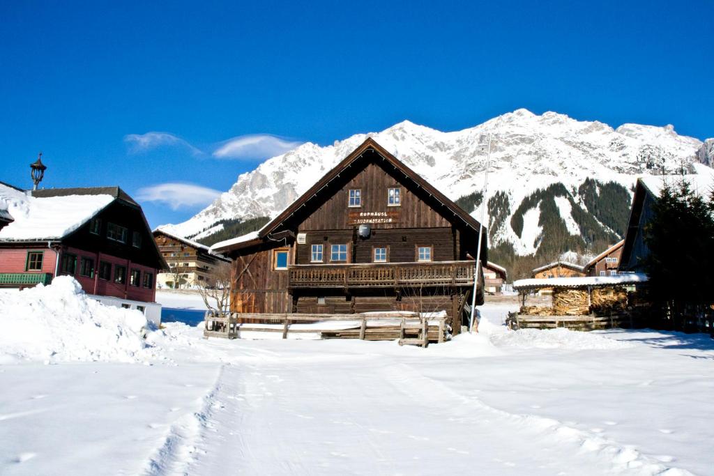 a log cabin in the snow with mountains in the background at Ruphäusl in Ramsau am Dachstein