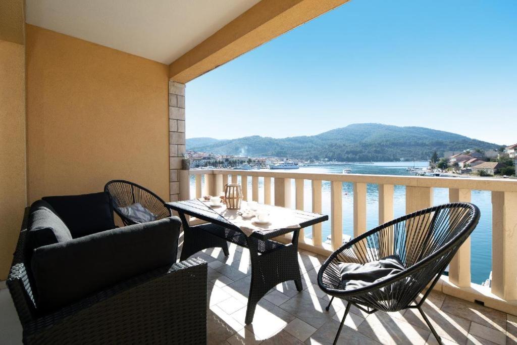 een balkon met een tafel en stoelen en uitzicht op het water bij Apartments Dea Caeli in Vela Luka