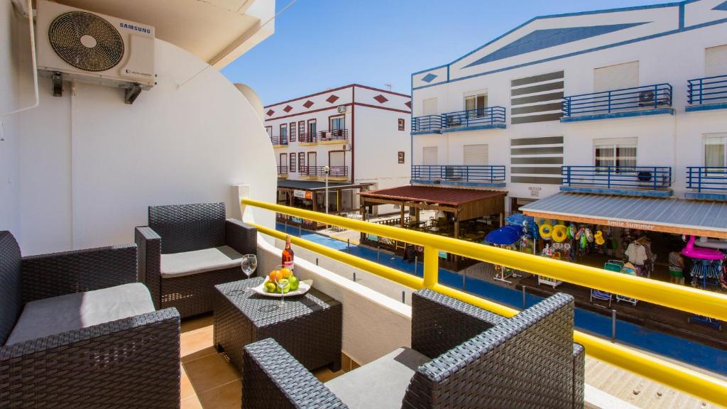 un balcone con sedie, tavoli e piscina di Apartamento T2 na Praia da Alagoa ad Altura