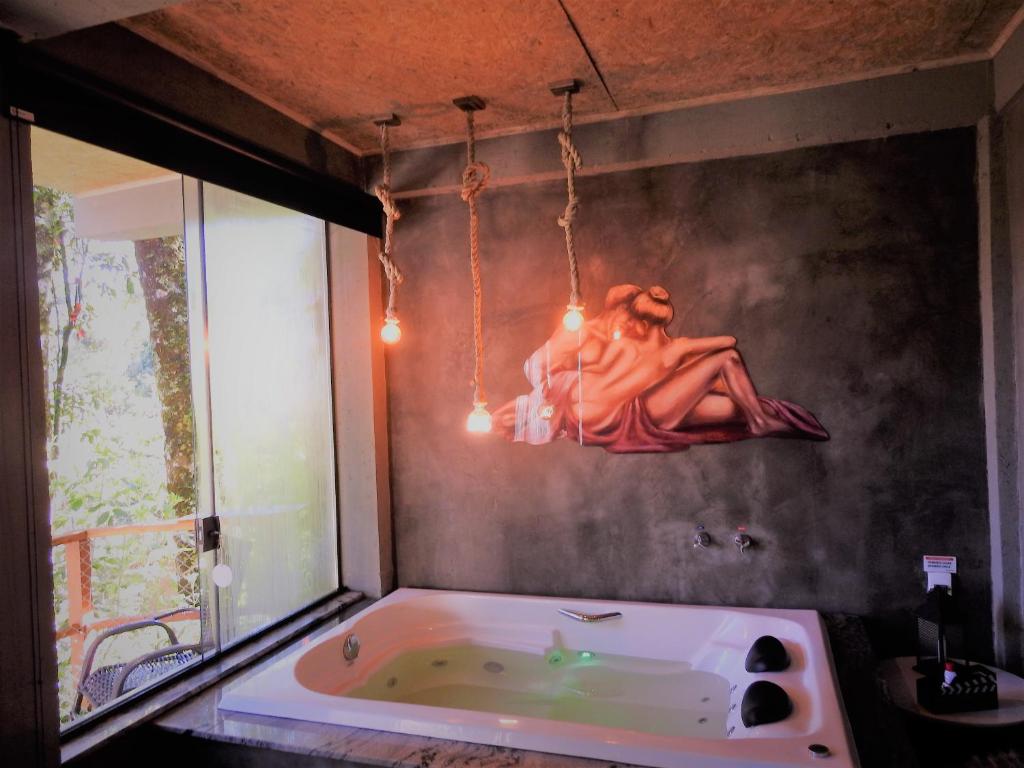 a bathroom with a tub with a woman sitting on the wall at Recanto Lira I in Monte Verde