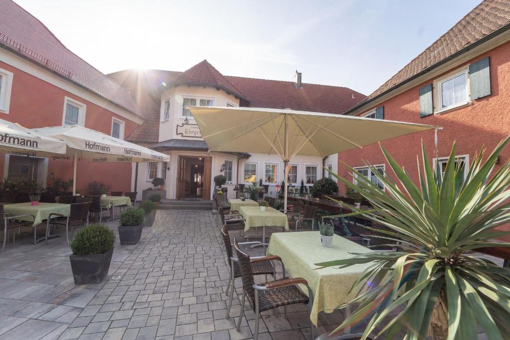 un patio con tavoli, sedie e ombrellone di Landgasthof im Ehegrund a Sugenheim
