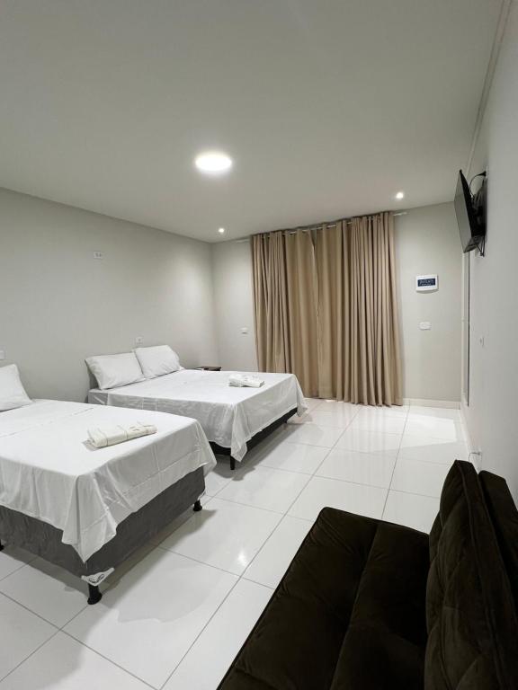 a hotel room with two beds and a television at JH Flats in Maragogi