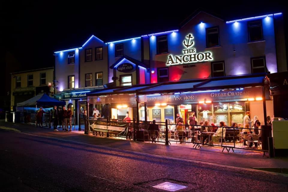 un groupe de personnes assises à l'extérieur d'un restaurant la nuit dans l'établissement Anchorage Inn, à Portstewart