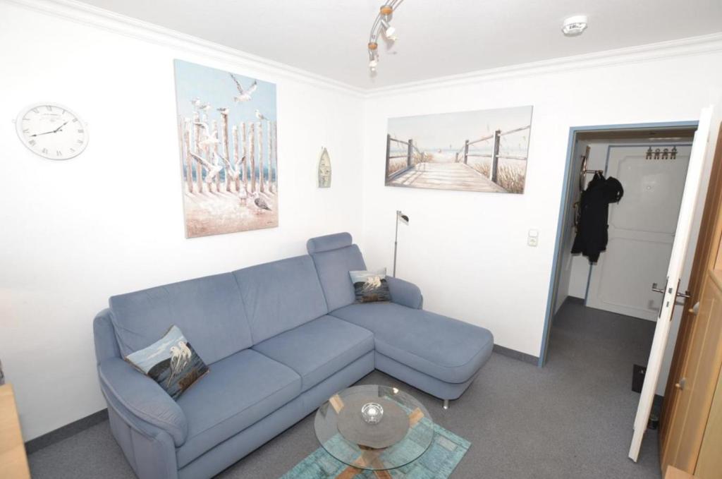 een woonkamer met een blauwe bank en een tafel bij Appartement-254 in Westerland