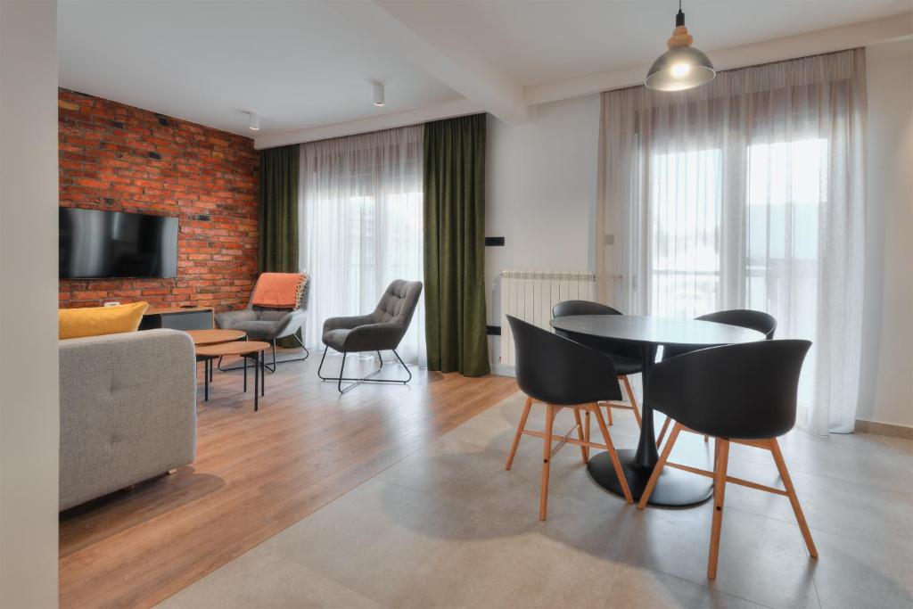 - un salon avec un canapé, une table et des chaises dans l'établissement Apartmani Studio Proforma, à Kolašin
