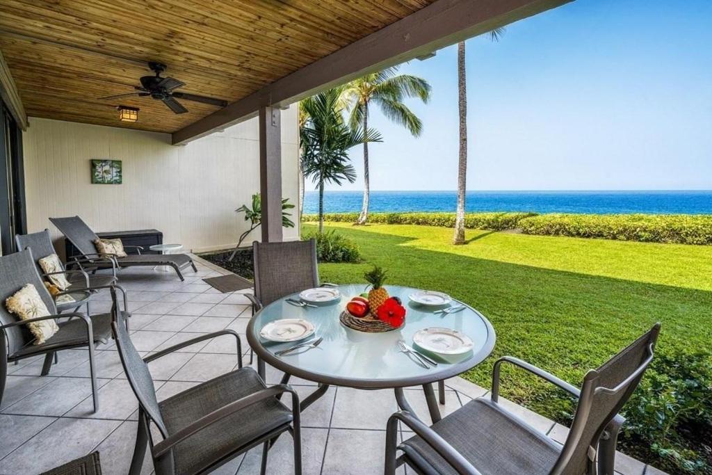 eine Terrasse mit einem Tisch, Stühlen und Meerblick in der Unterkunft Keauhou Kona Surf & Racquet Club #4-102 in Kailua-Kona