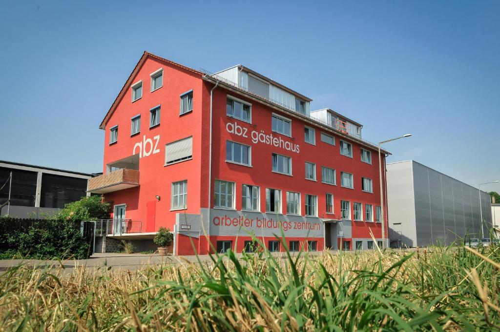 un bâtiment rouge au milieu d'un champ dans l'établissement Gästehaus abz Stuttgart, à Stuttgart