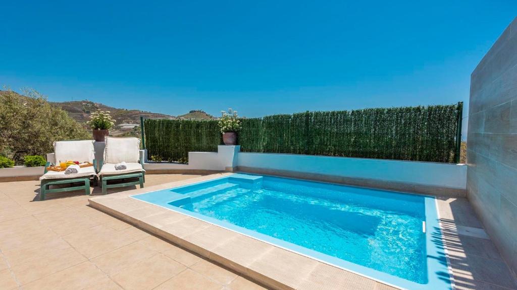 - une piscine sur une terrasse avec 2 chaises à côté d'une clôture dans l'établissement Casa Noela Torrox by Ruralidays, à Torrox