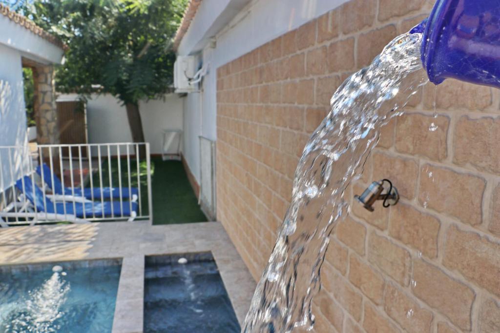 una fuente de agua frente a una pared de ladrillo en Chalet La Roa III, en Conil de la Frontera