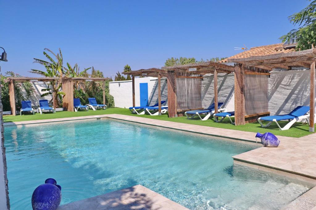 a swimming pool with blue chairs and a resort at Chalet La Roa III in Conil de la Frontera