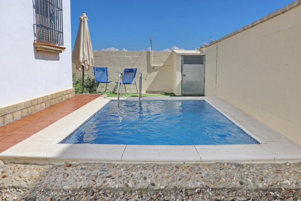a small swimming pool with an umbrella and chairs at Chalet Chaparrillo Conil in Conil de la Frontera