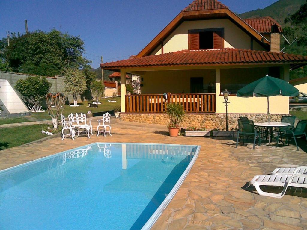 a house with a swimming pool in front of a house at Chacara na Serra da Mantiqueira in Santo Antônio do Pinhal