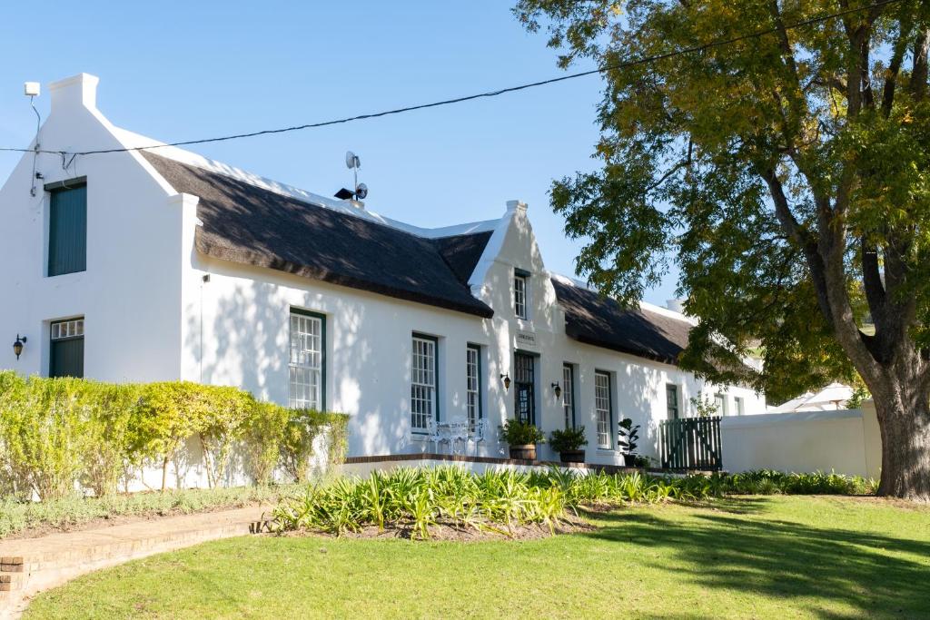 a white house with a tree in the yard at Laborie Jonkershuis in Paarl