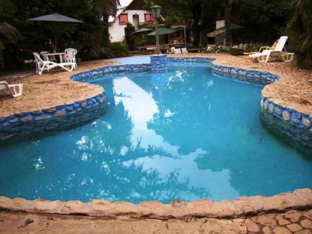 duży niebieski basen z kamieniami wokół niego w obiekcie Hotel Alihuen w mieście Sierra de la Ventana