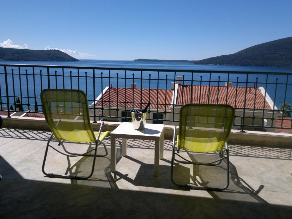 2 sillas y una mesa en un balcón con vistas al agua en Apartment Royal Savina-free garage, en Herceg-Novi
