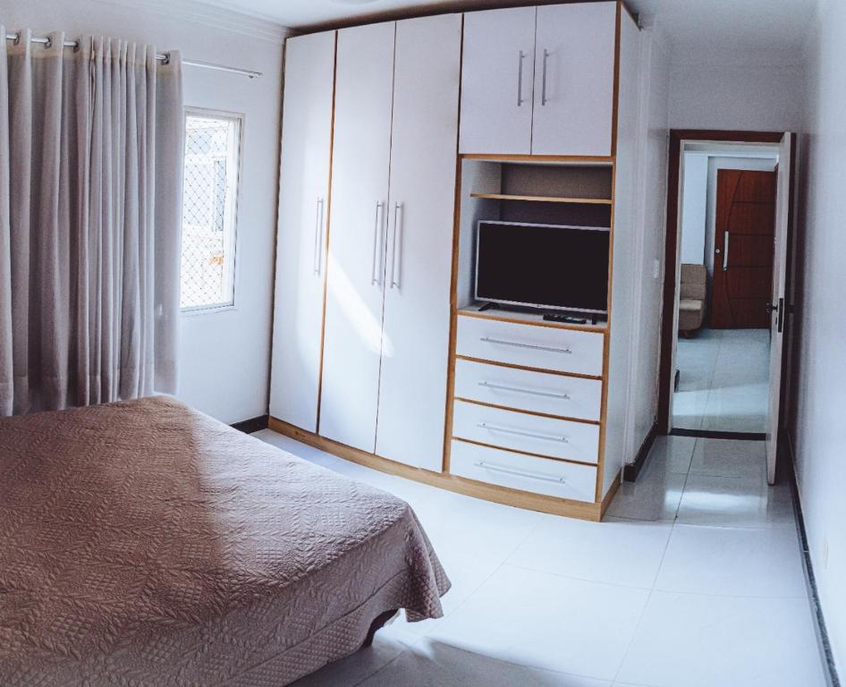 a bedroom with a bed and a cabinet with a television at 100 metros da praia das Castanheiras,com garagem, internet, cadeiras de praia, cooler,roupas de cama e banho in Guarapari