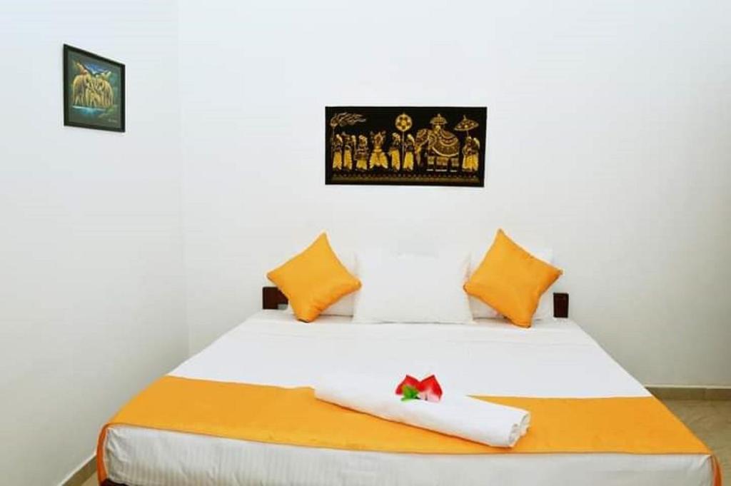 a bedroom with a white bed with orange pillows at Villa DeLorenta in Anuradhapura
