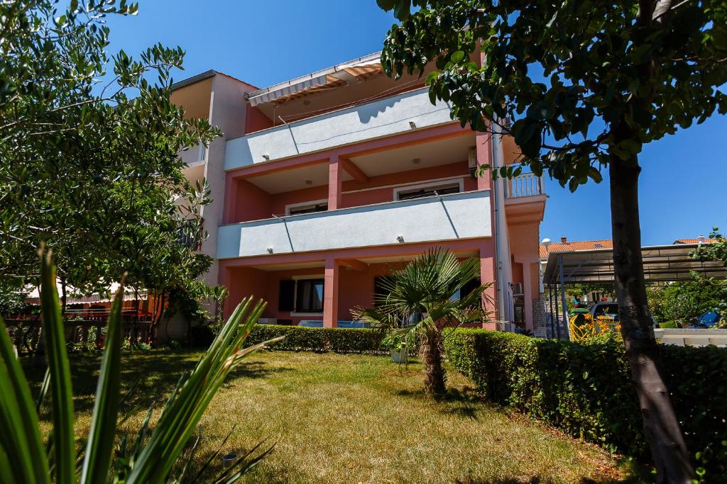 a pink building with a yard in front of it at Apartments Stupar in Krk