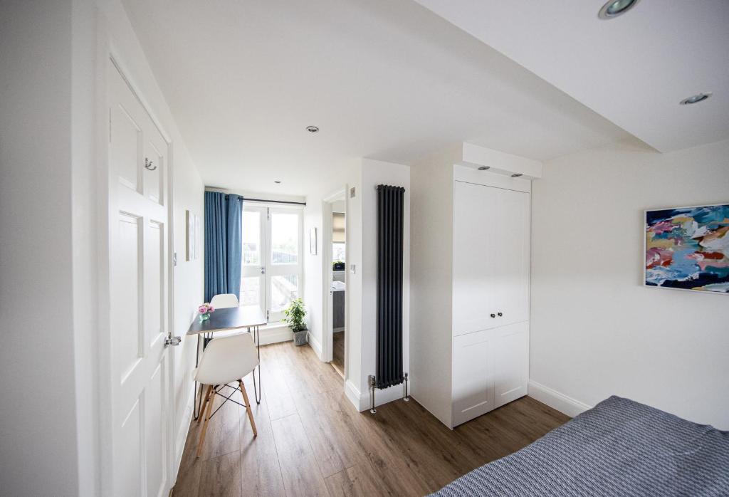 a white room with a bed and a desk at Wimbledon Park Bed & Breakfast in London