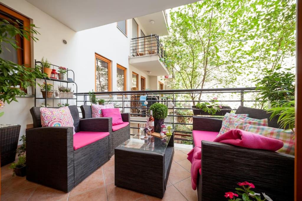 einen Balkon mit Sofas und einem Tisch mit rosa Kissen in der Unterkunft Best Downtown Apartman in Budapest