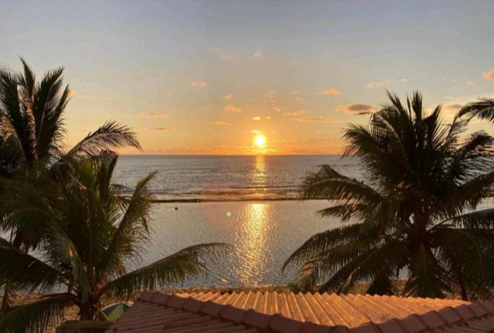 una puesta de sol sobre el océano con palmeras y una piscina en Coral Reef Guest, en Beruwala