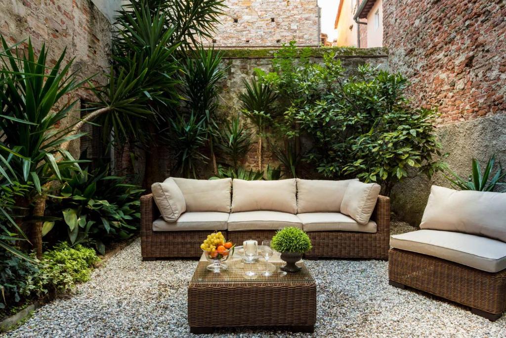 een patio met een bank, een tafel en planten bij Casa Santa Zita, A Toproof Penthouse Apartment with Elevator and Private Garden Inside the Walls in Lucca