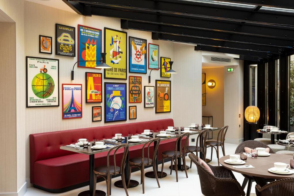 ein Restaurant mit Tischen, Stühlen und Plakaten an der Wand in der Unterkunft Hôtel Moderniste in Paris