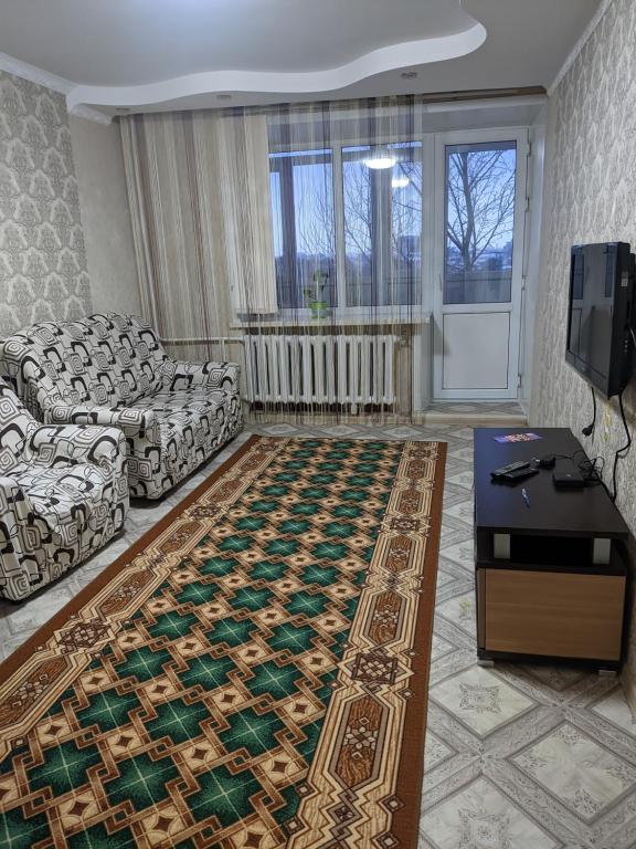 uma sala de estar com um sofá e um tapete em Квартира в районе жд вокзала em Shchuchinsk