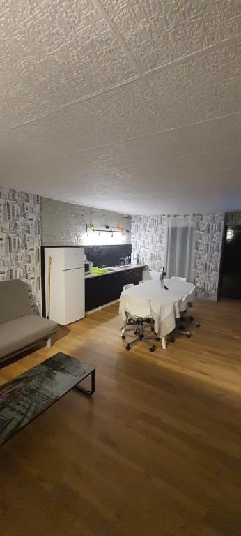 Großes Zimmer mit einem weißen Tisch und einem Sofa in der Unterkunft T3 tout confort pour 6 couchages in Hazebrouck