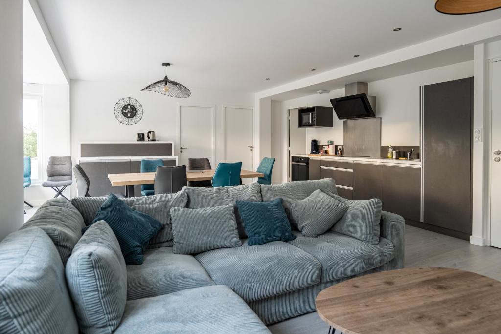 a living room with a blue couch and a kitchen at Salicorne in Frehel